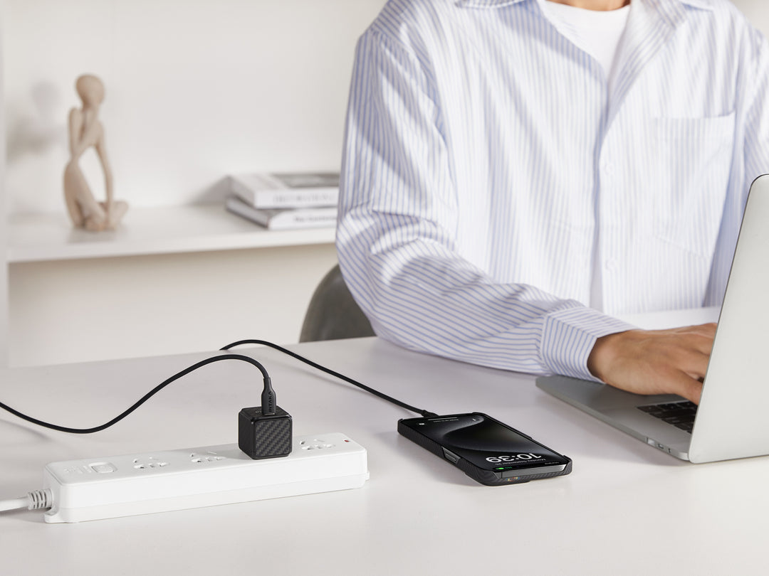 Carbon fiber patterned GaN charger connected to an iPhone, offering a modern charging solution.
