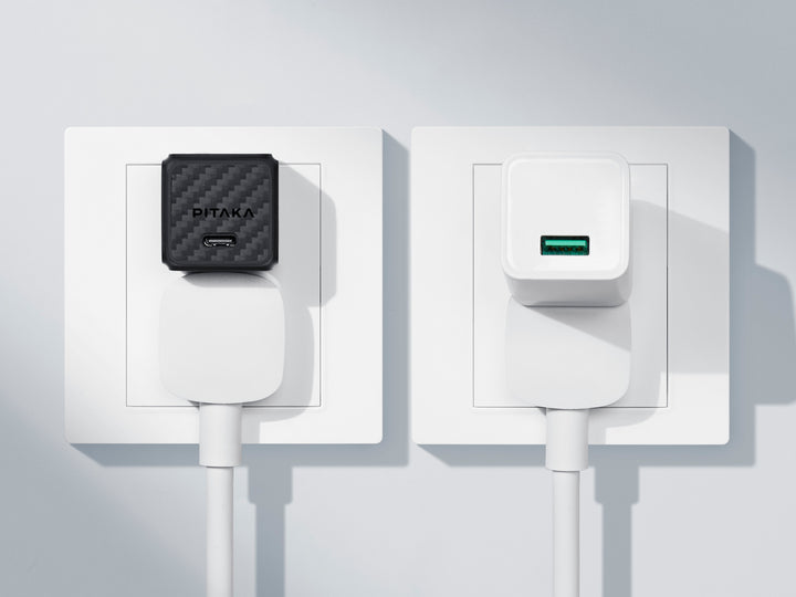 "Sleek carbon fiber GaN charger plugged into a wall socket beside a traditional white charger.