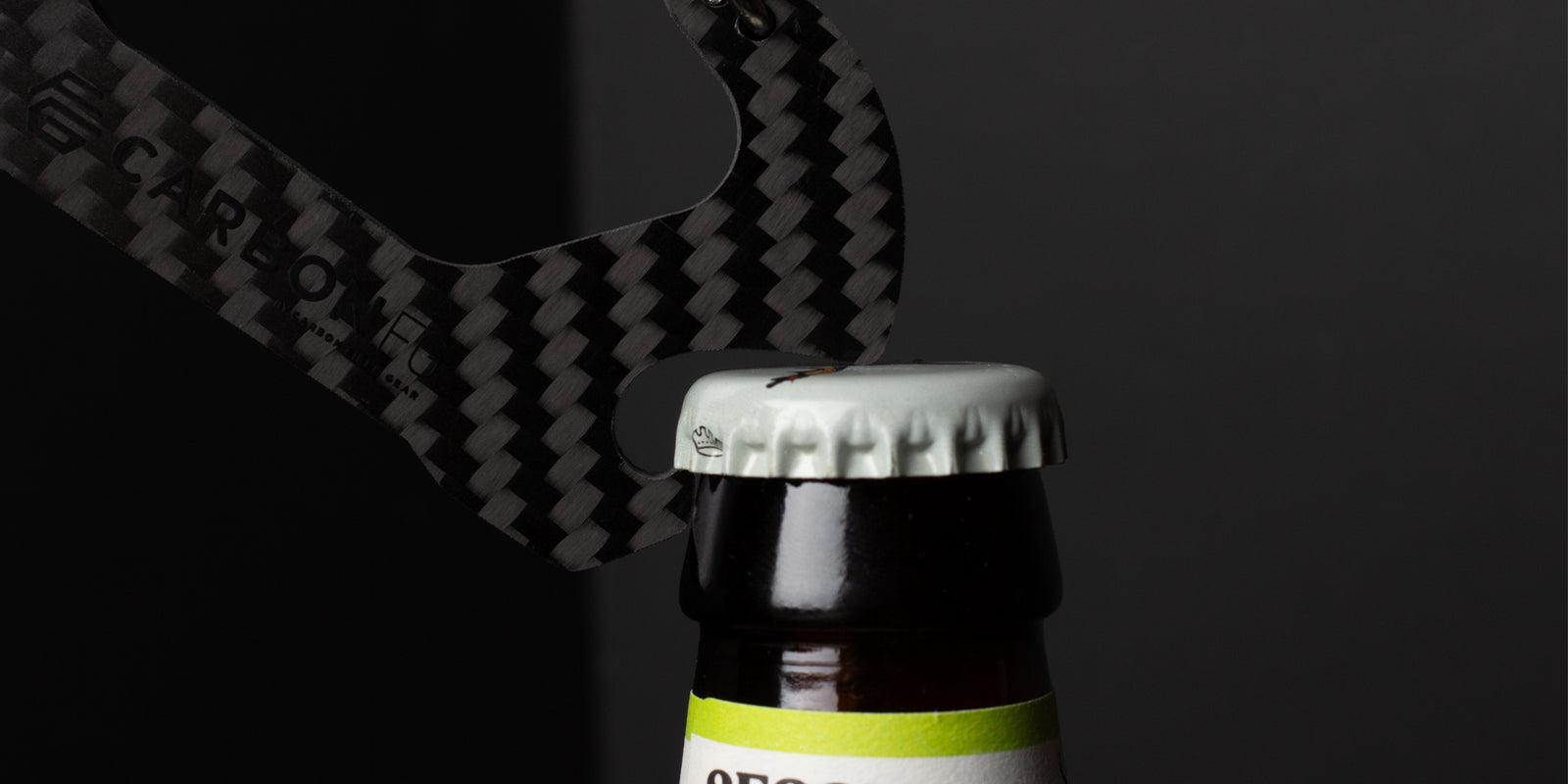 CarbonFG Carabiner Bottle Opener effortlessly opening a bottle, highlighting its practical design and carbon fiber construction.