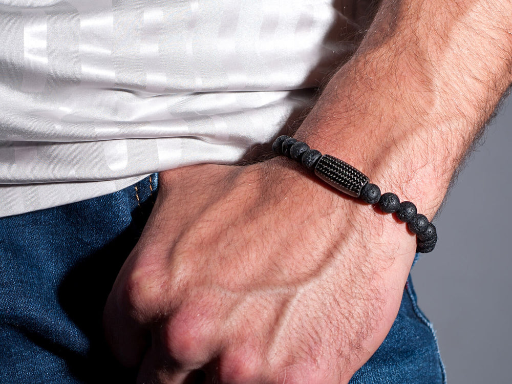 Carbon Fiber and Lava Rock Beaded Bracelet worn on a man's wrist with white shirt and blue jeans, showing how the bracelet looks when styled with casual attire.